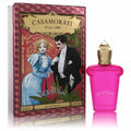 Vibrant pink Casamorati Gran Ballo 1 oz EDP bottle, topped with a golden cap, next to its ornate vintage-illustrated red and gold box.