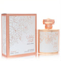 Stunning Nusuk Ishq Al Ward unisex Eau De Parfum spray, 3.4 oz. Features a luxurious rose gold bottle and box with elegant white rose patterns.