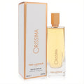 Ted Lapidus Orissima 3.3 oz women's Eau De Parfum. Sleek clear bottle with golden liquid and cap, next to its elegant white and gold box.