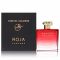 Bold Roja Danger Pour Homme men's fragrance. Striking red glass bottle with gold cap, beside its elegant black Roja Parfums box.