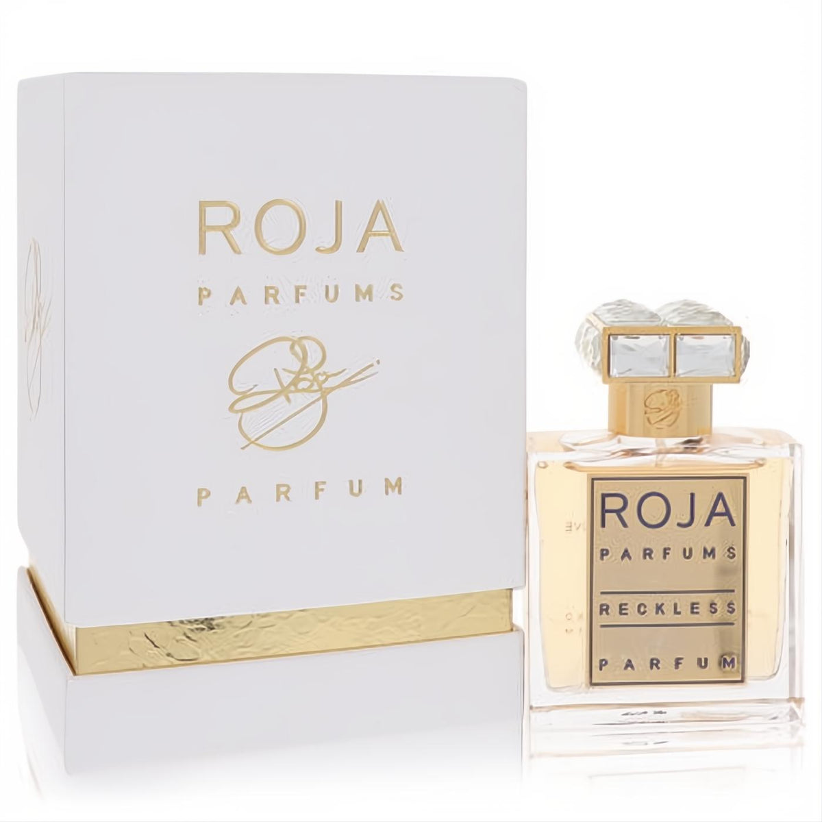 Roja Reckless Eau De Parfum spray: stunning clear glass bottle with gold label and crystal cap, beside its chic white and gold box.