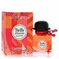 Twilly d'Hermès Eau Poivrée 1.7 oz perfume. Amber liquid in a chic bottle with black hat cap and signature ribbon, next to its vibrant red and orange box.
